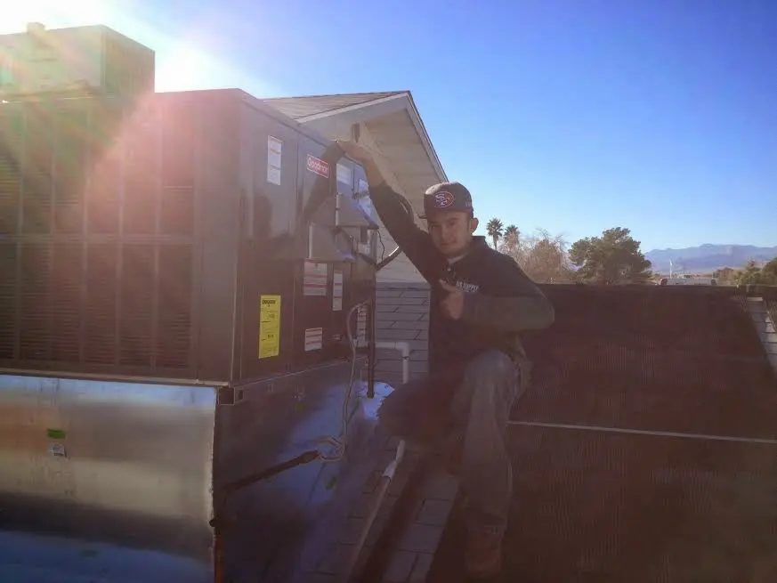 HVAC technician performing AC Tune-Up on a rooftop unit in Woodbury